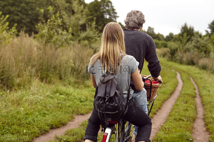 一对夫妇在乡村土路上骑自行车的