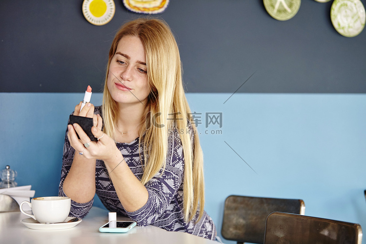 一名年轻女子独自在咖啡馆涂口红