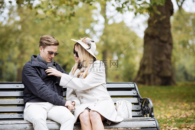 坐在公园长椅上的时尚年轻夫妇英
