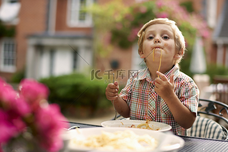 一个男孩坐在花园里的桌子边一边