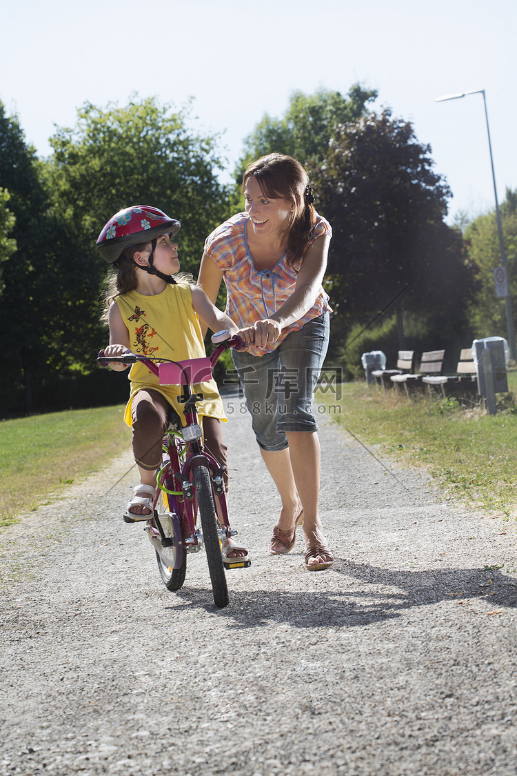 小女孩和妈妈一起学骑自行车