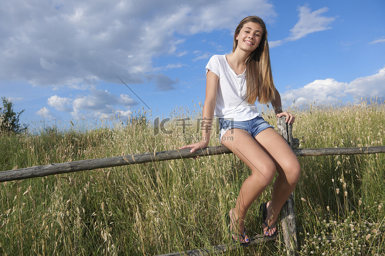 十几岁的女孩坐在木栅栏上意大利
