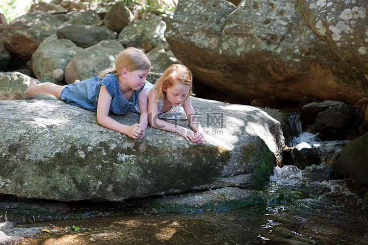 女孩们躺在河边的岩石上