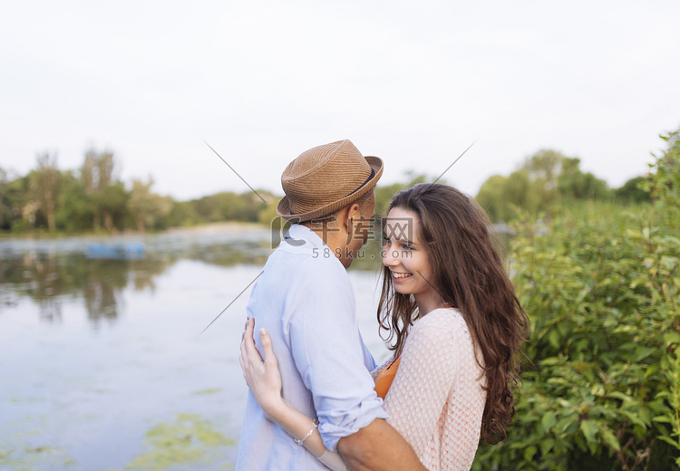 年轻夫妇在湖边拥抱的侧观