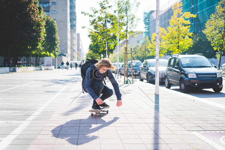 年轻的男子滑板运动员蹲在人行道