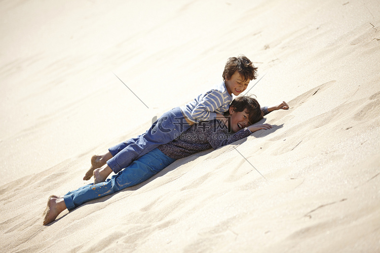 两个小男孩躺在沙丘上玩耍