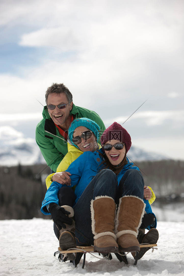 三个朋友坐在雪地里的雪橇上