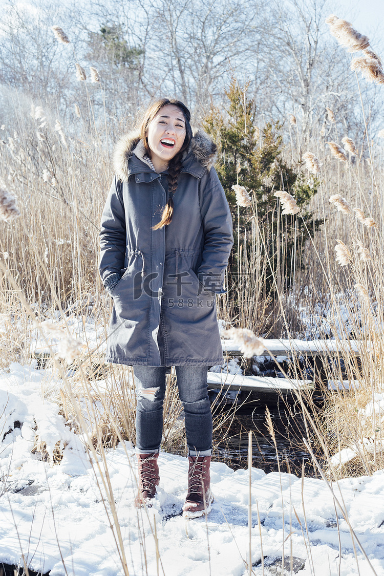 穿着冬衣的女子在雪地上微笑着看