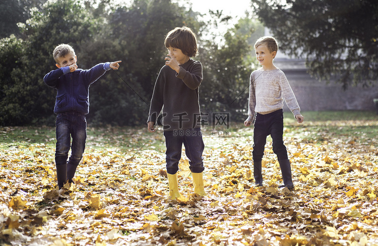 三个男孩在户外玩耍在秋叶里