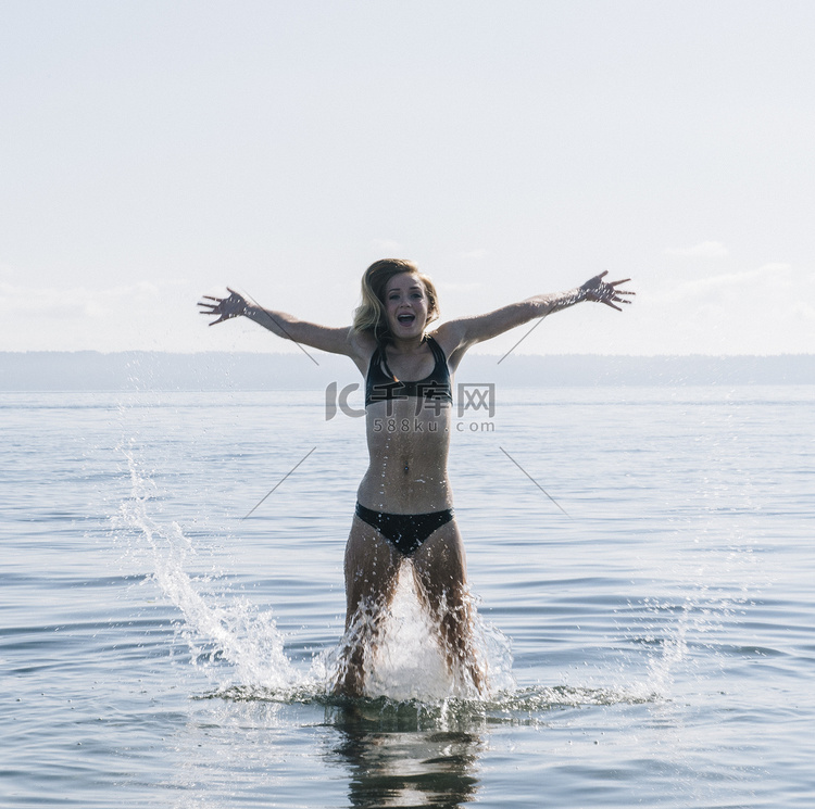十几岁的女孩站在海里溅起水来