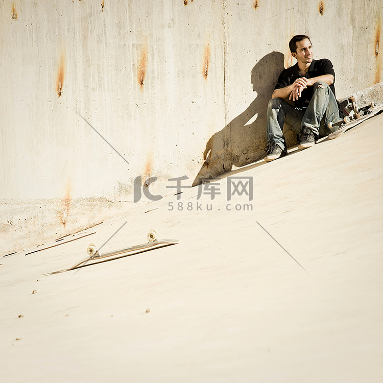 坐在混凝土斜坡上的滑板运动员