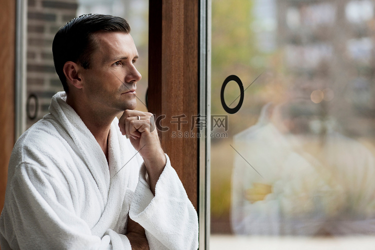一名身着浴袍的男子望着窗外