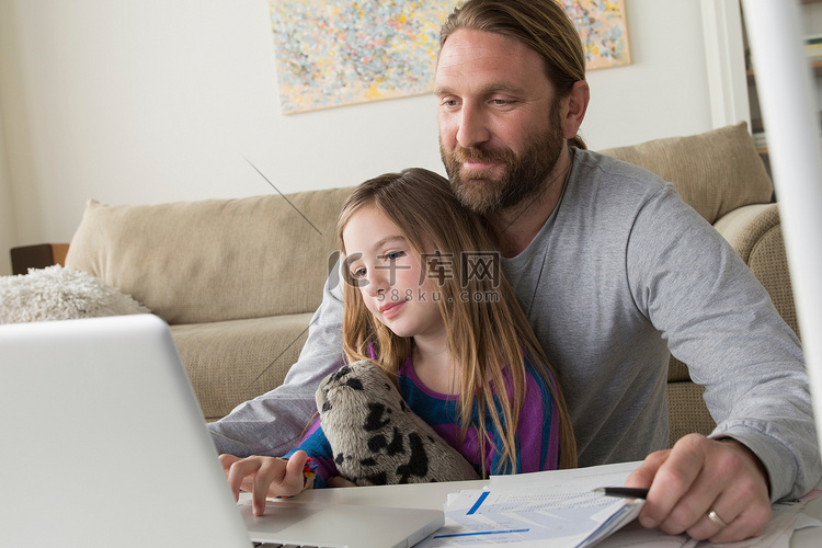 父亲带着孩子使用笔记本电脑
