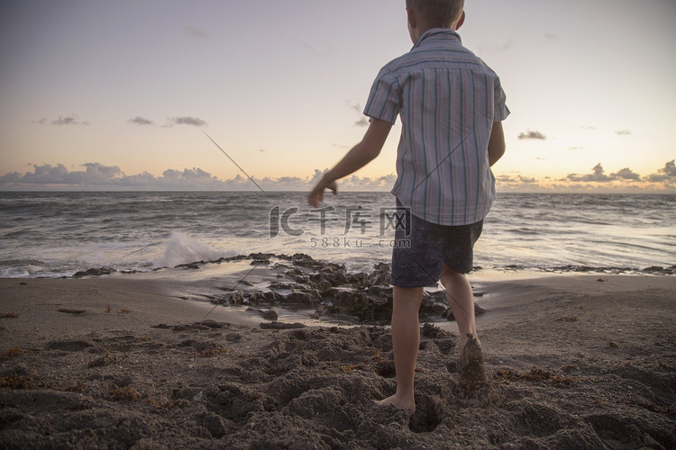 日出时男孩在海滩上玩耍的后景美
