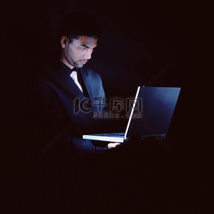 黑暗中拿着笔记本电脑的商人
