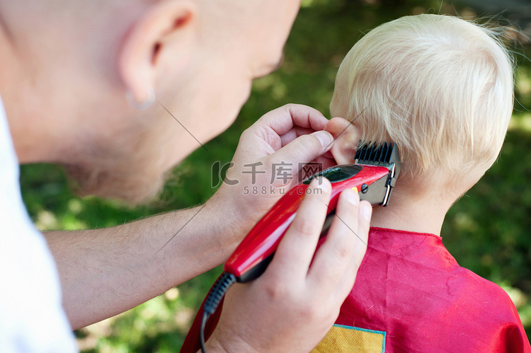 父亲用剪刀给蹒跚学步的儿子理发