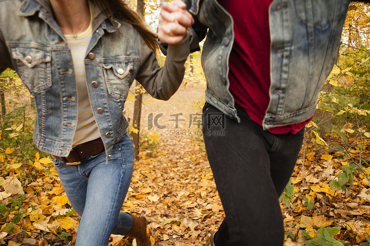 浪漫的年轻情侣在秋日森林中奔跑