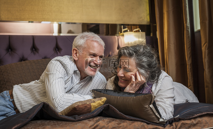 一对老年夫妇在床上微笑着聊天