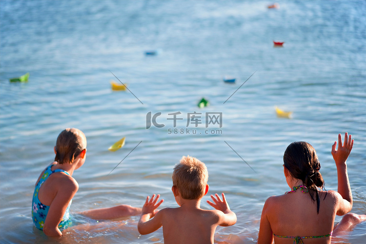 孩子们在海滩上漂浮着纸船