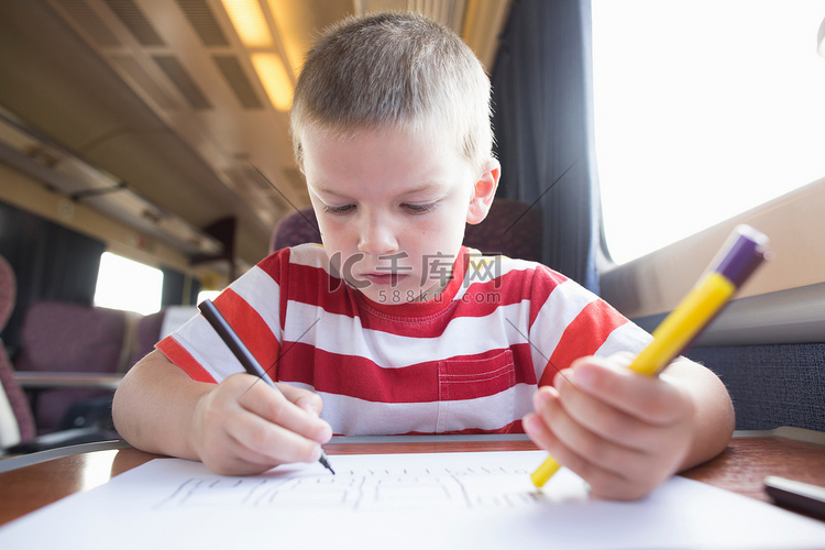 火车上拿着笔笔和纸的小男孩