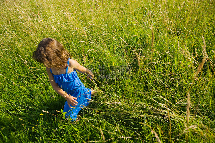 一个女孩走在一片长长的草地上