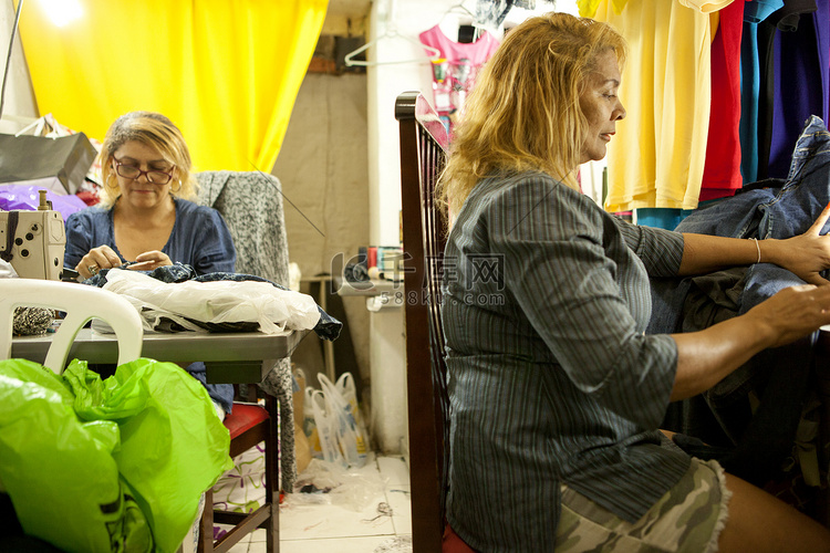 两名女裁缝在车间的缝纫机前工作