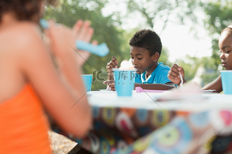 生日聚会上坐在野餐桌旁的孩子们