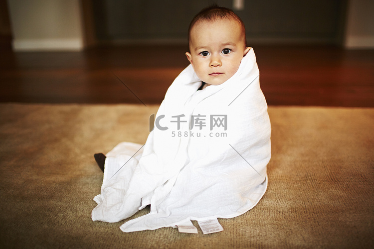 坐在地板上用毯子包裹的男婴肖像