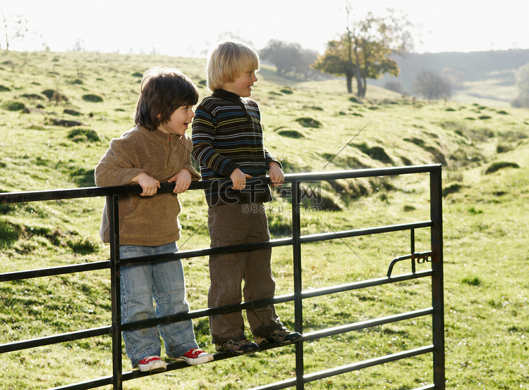两个男孩在乡间的大门上荡秋千