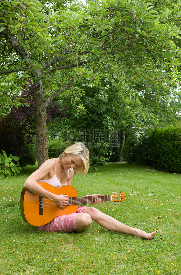 在花园里弹吉他的女人