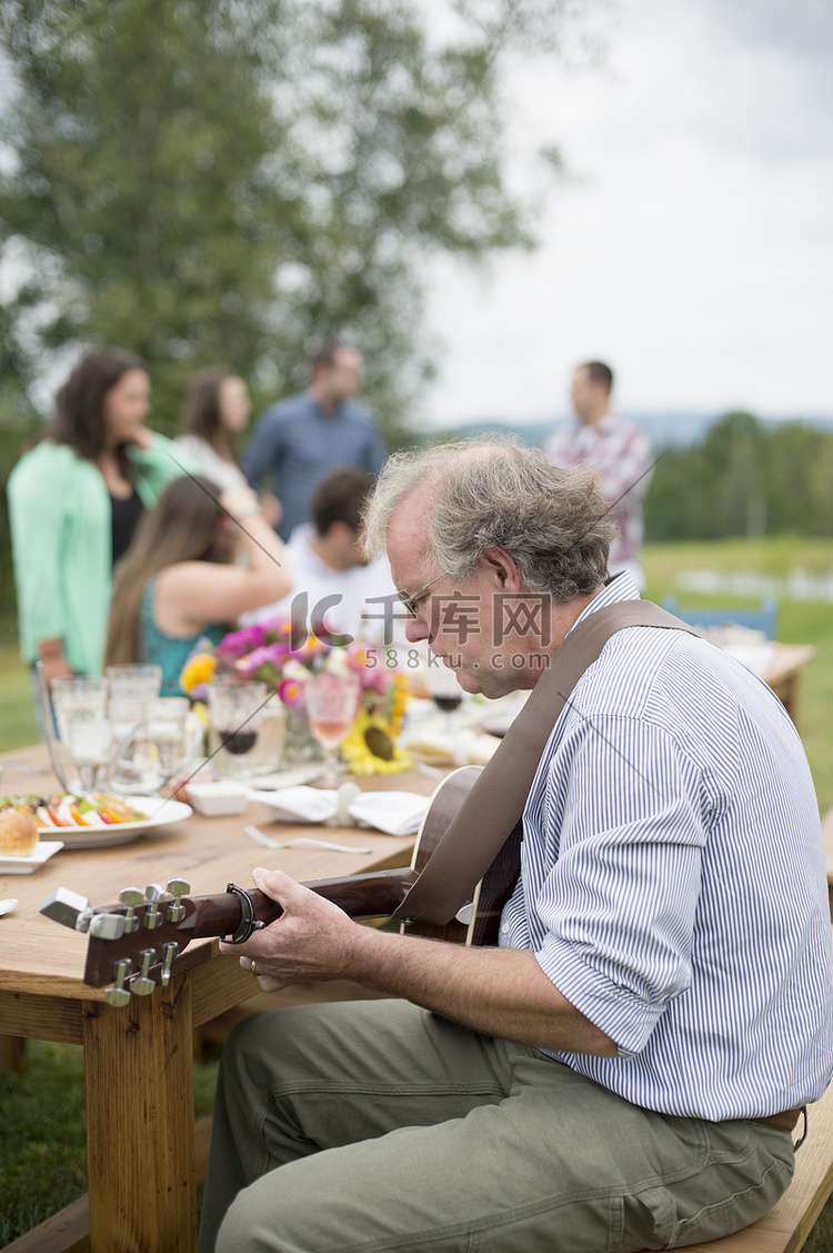 成熟的男人弹着吉他朋友和家人饭