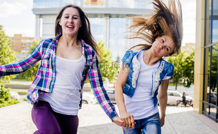 两个年轻女子甩着头发在城市里奔
