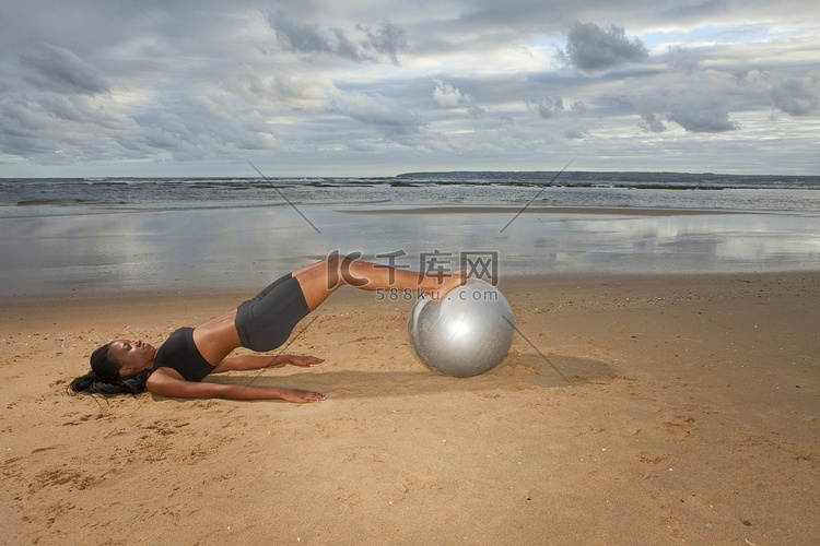 一名年轻女子在海滩上用健身球练