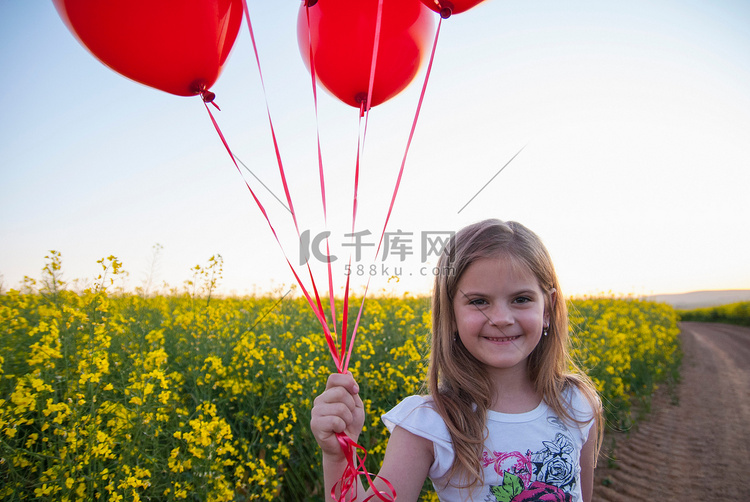在土路上背着气球的女孩