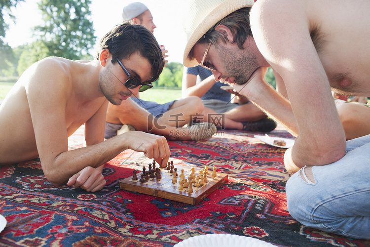 两个年轻人在日落公园聚会上玩棋
