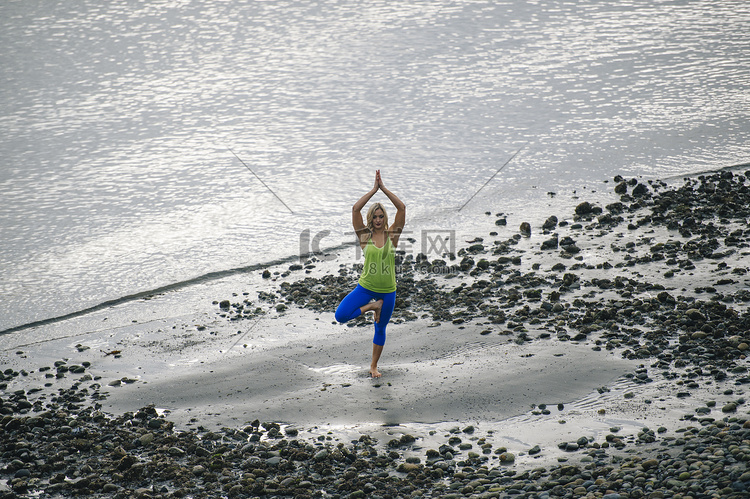 在海滩上练习瑜伽的年轻女子站在