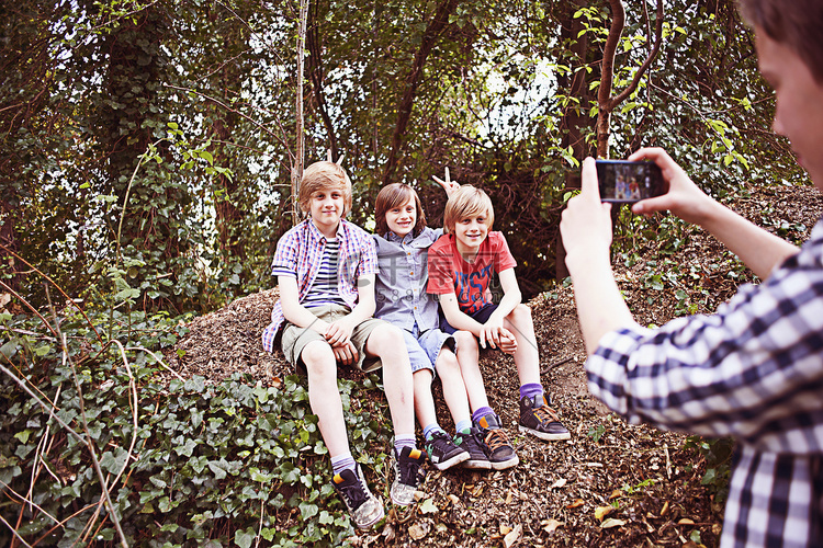 男孩在森林里用手机给朋友拍照