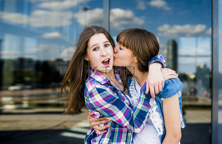 两个年轻女子鬼混拥抱亲吻脸颊