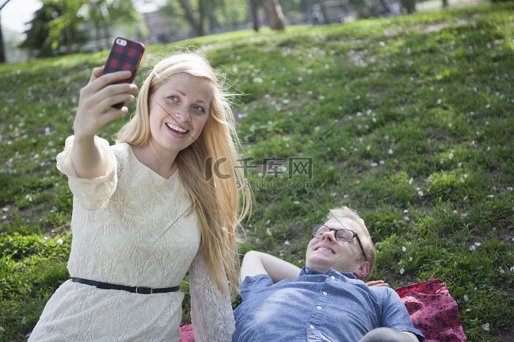 一对年轻夫妇在公园里用智能手机