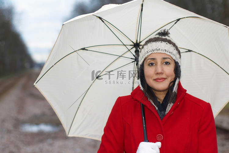 公园里穿红色夹克带雨伞的女孩