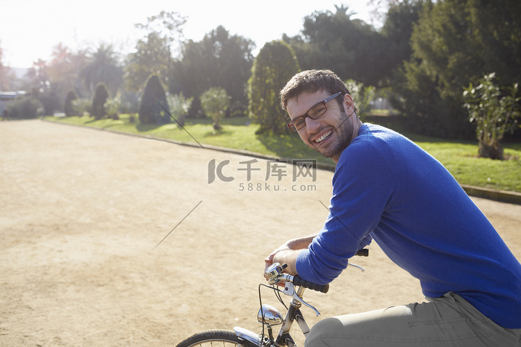 公园里坐在自行车上的中年男子微