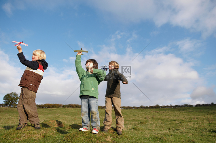男孩们在田野里扔玩具飞机