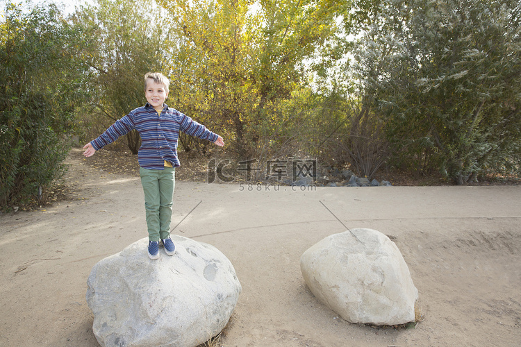 公园里站在巨石上的男孩的肖像