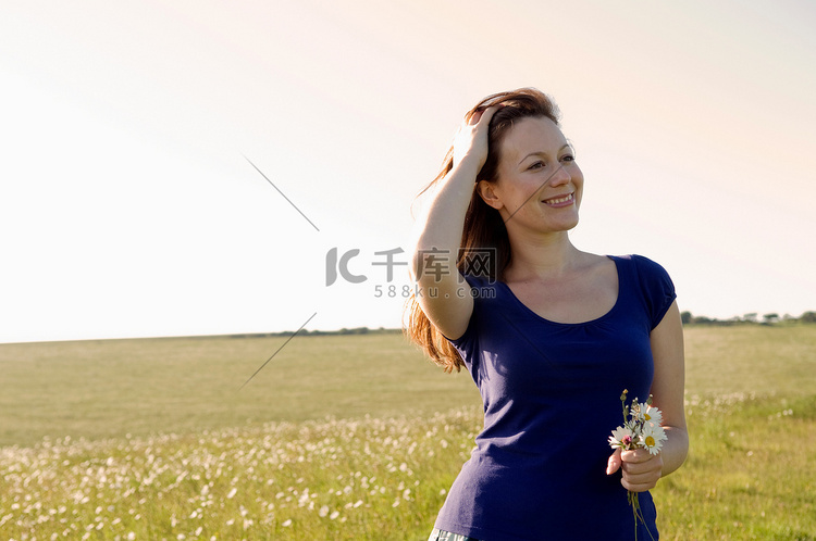 微笑的女人在草地上捧着鲜花
