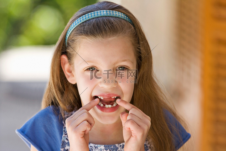一名年轻女孩指着她缺失的牙齿