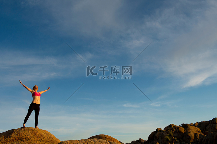 一位年轻女子张开双臂站在沙漠中