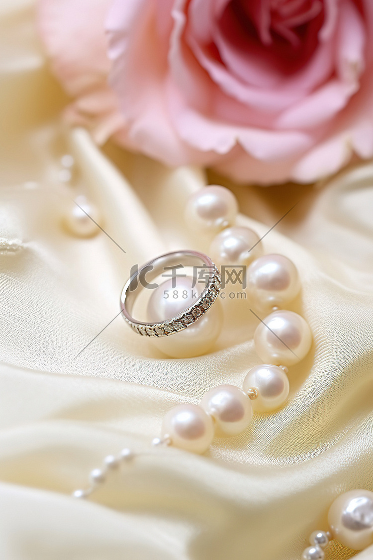 金戒指放在带有粉红色珍珠的白布