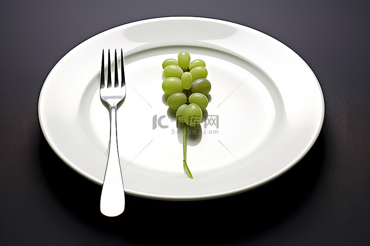 盘子里有一群绿葡萄和叉子