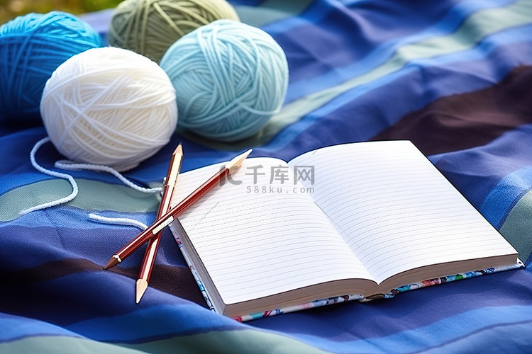 一本笔记本放在三个毛线球和织针