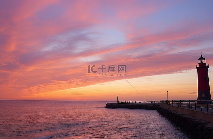 日落时码头和灯塔上空的粉红色天